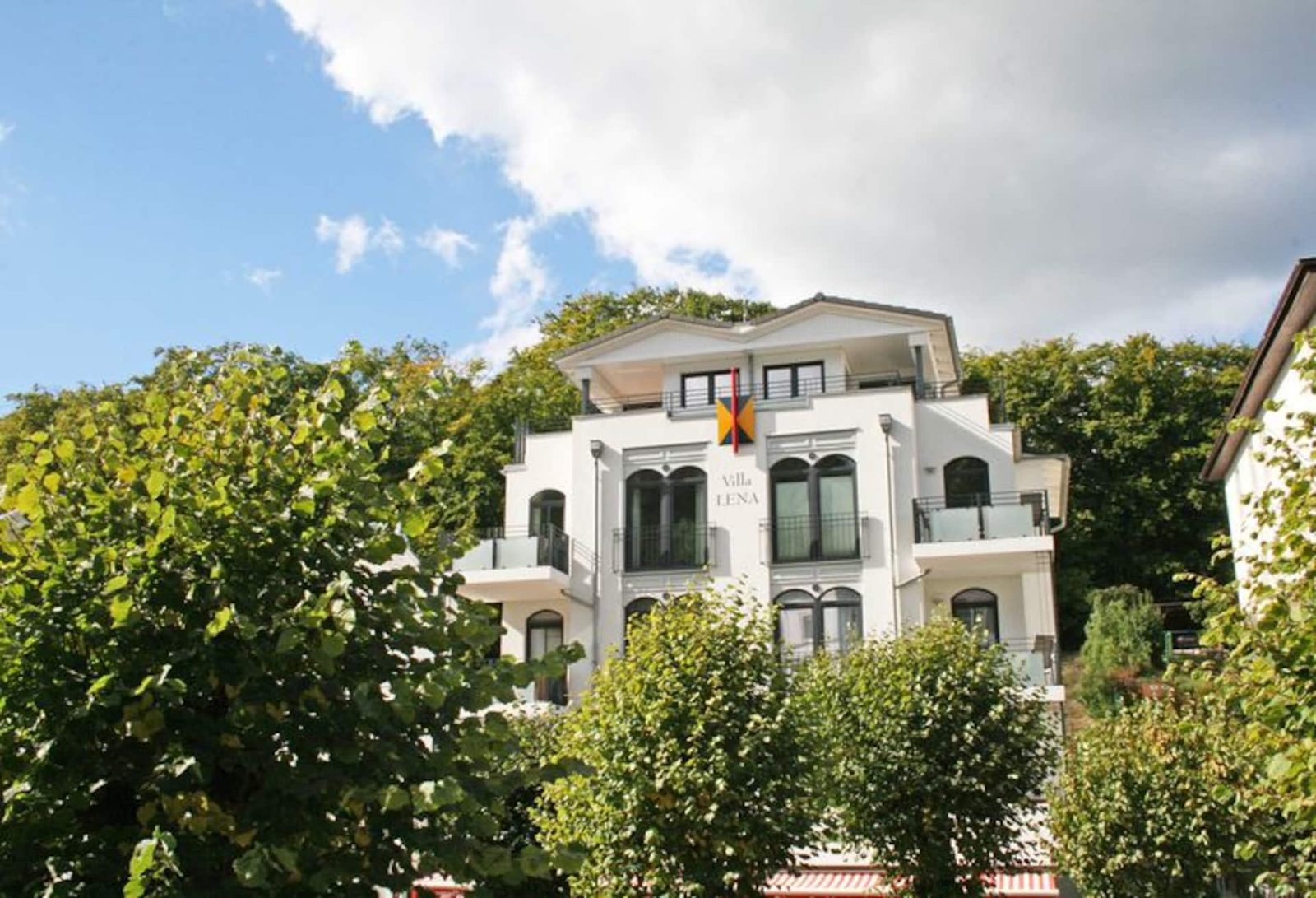 Die weiße Fassade der Villa Lena in Sellin, eingerahmt von Bäumen
